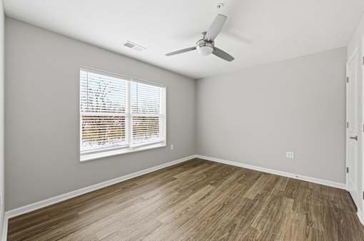 A room with a ceiling fan and a window with blinds.