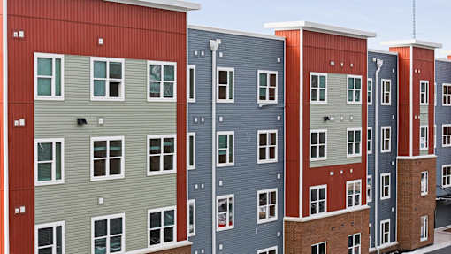 A row of multi-story buildings with red, grey, and blue exteriors.
