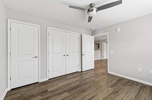 A room with a ceiling fan and four doors.