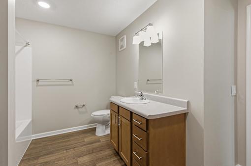 A bathroom with a toilet, sink, and mirror.