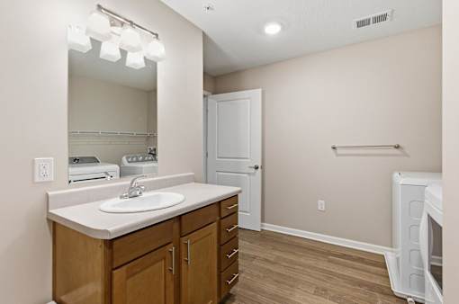 A bathroom with a sink, mirror, and wooden cabinets.