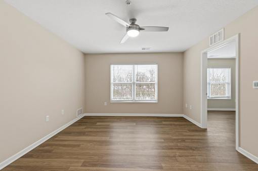 A room with a ceiling fan and wooden flooring.