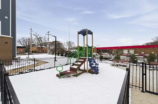 A playground with a slide and swings covered in snow.
