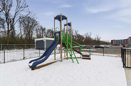 A playground with a blue and green slide in the snow.