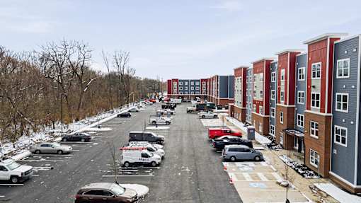 A parking lot with cars and apartment buildings on the side.