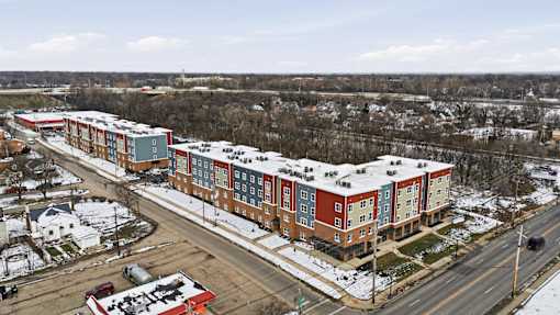 A large apartment complex is surrounded by a parking lot and a road.