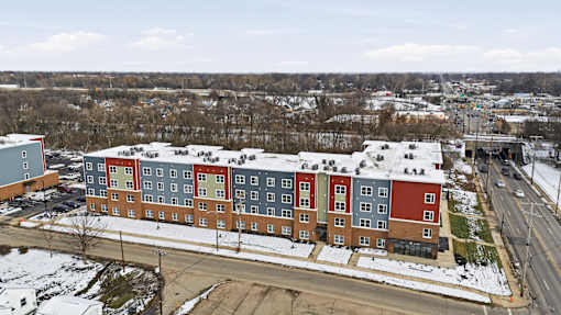 A large multi-story building with red and blue sections is surrounded by snow.