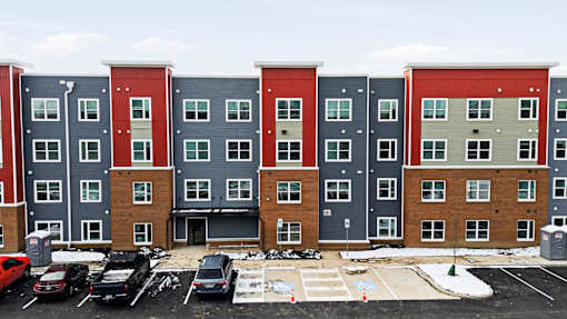 Apartment building with a parking lot in front.