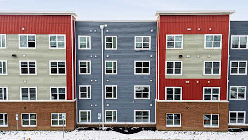 A row of multi-story buildings with red, blue, and beige exteriors.