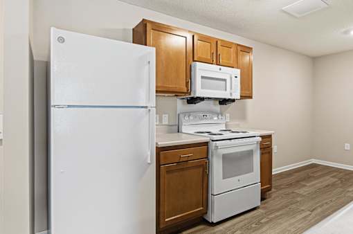 A white refrigerator is in a kitchen with wooden cabinets.