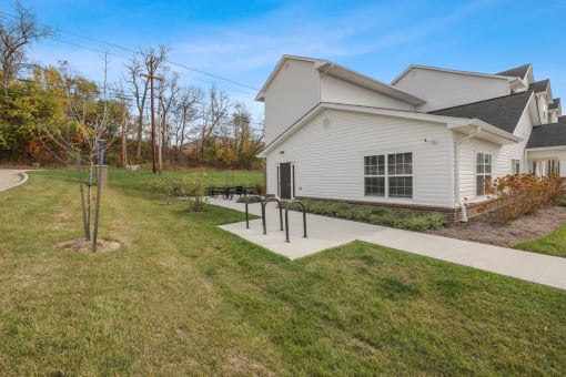 a white house with a sidewalk in front of it and a yard with a grass