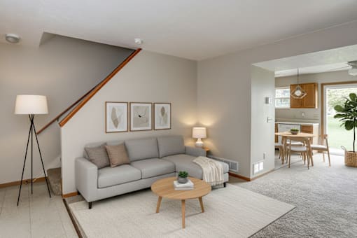 A living room with a grey couch, a wooden coffee table, and a lamp on a tripod.