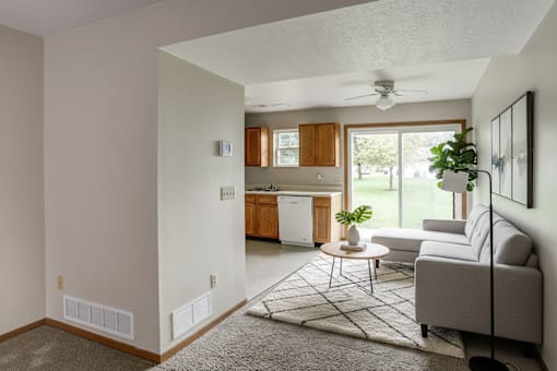 A living room with a grey couch and a rug.