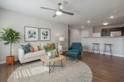 A living room with a white couch, a blue chair, and a rug.