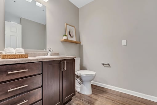 A bathroom with a toilet, sink, and wooden cabinets.