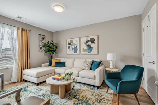 A living room with a white couch, a blue chair, and a rug.