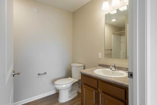 A bathroom with a toilet, sink, and mirror.