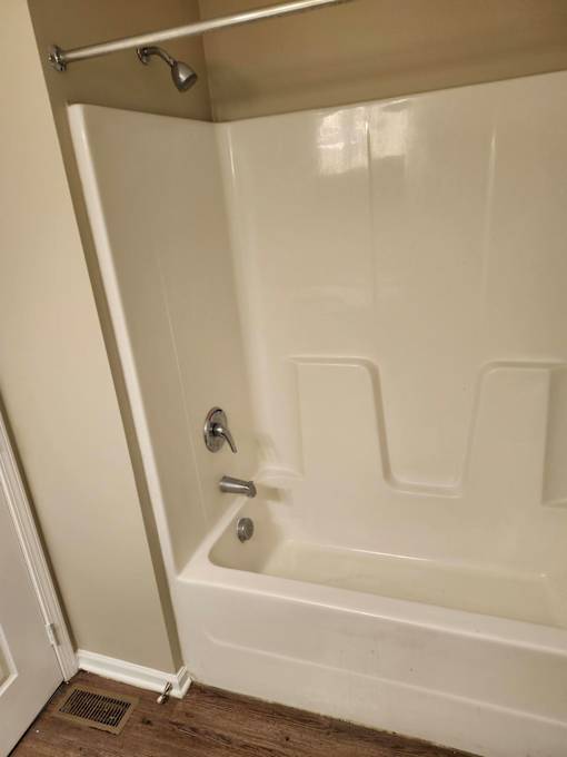 A white bathtub with a silver faucet and a silver shower head.