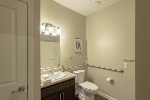 A bathroom with a toilet, sink, and mirror.