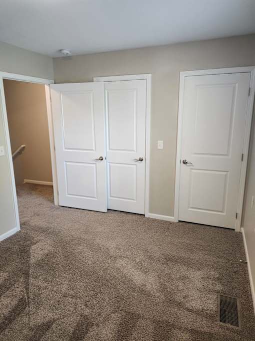 A room with three white doors and a carpeted floor.