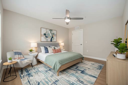 A bedroom with a bed, chair, and rug.