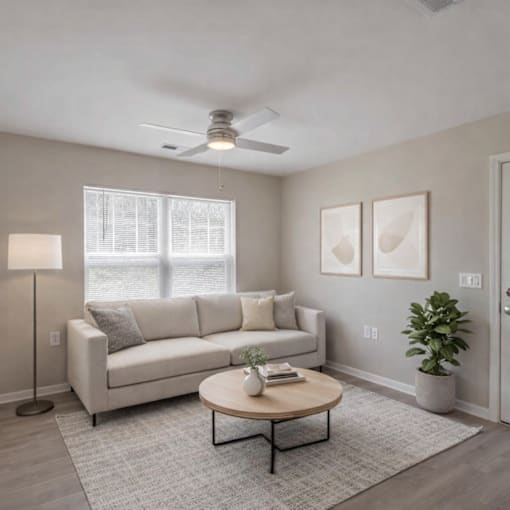 A living room with a white couch, a coffee table, and a ceiling fan.