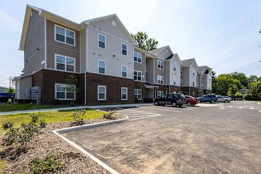A parking lot in front of a multi-story apartment building.