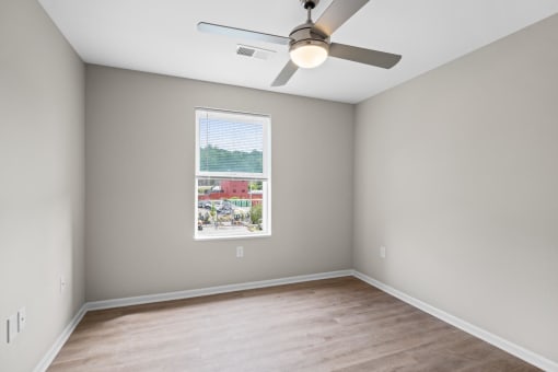 an empty room with a window and a ceiling fan