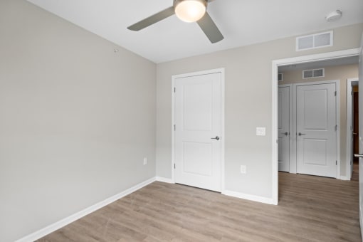 a bedroom with a ceiling fan and a door to a closet