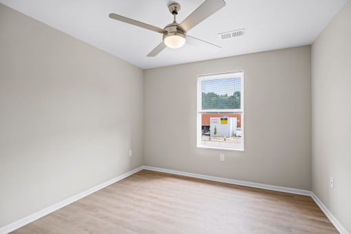 an empty room with a ceiling fan and a window