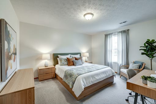 A bedroom with a large bed, a chair, and a painting on the wall.