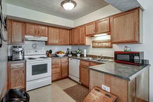 A kitchen with wooden cabinets and a white stove top oven.