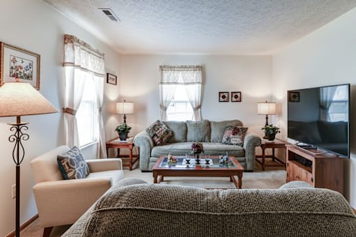 A living room with a couch, chair, lamp, and television.