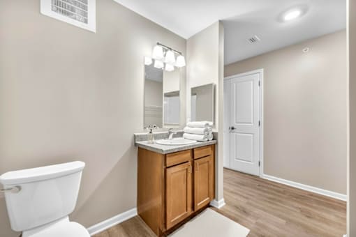 A bathroom with a white toilet and a wooden vanity.