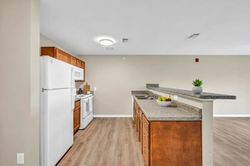 A kitchen with a white refrigerator, wooden cabinets, and a marble countertop.