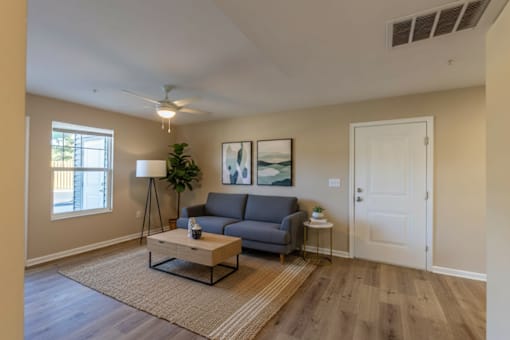 A living room with a grey couch, a coffee table, and a ceiling fan.