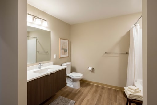 A bathroom with a toilet, sink, and mirror.