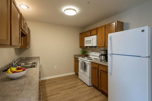 A kitchen with a white refrigerator, wooden cabinets, and a sink.