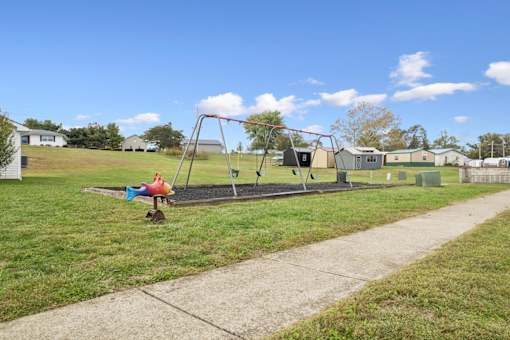 A playground with a swing set and a red slide.