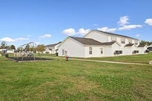 A white building with a playground in front of it.