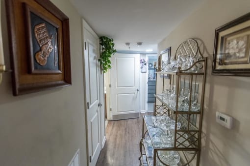 a hallway with a shelf of glasses and a door to a room with a staircase