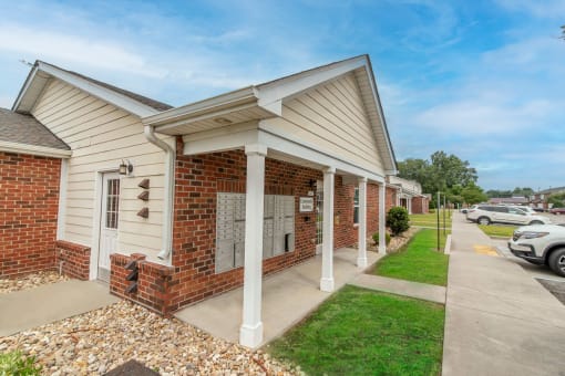 a brick and white building with a sidewalk in front of it and a parking lot in the