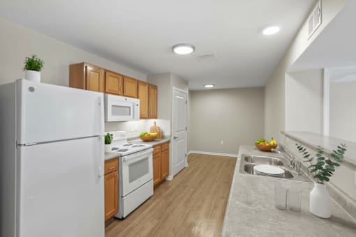 A kitchen with a white refrigerator, wooden cabinets, and a white countertop.