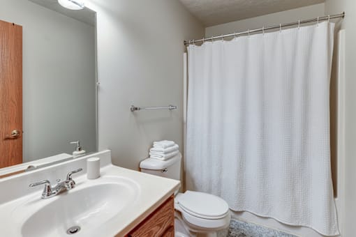 A white bathroom with a toilet, sink, and shower curtain.
