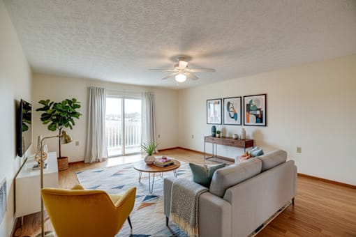 A living room with a yellow chair and a grey couch.