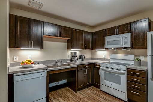 A kitchen with white appliances and wooden cabinets.