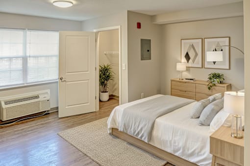 A bedroom with a bed, nightstand, and window.