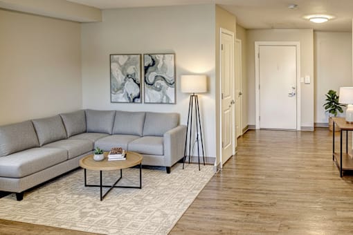 A living room with a grey sofa, a coffee table, and a painting on the wall.