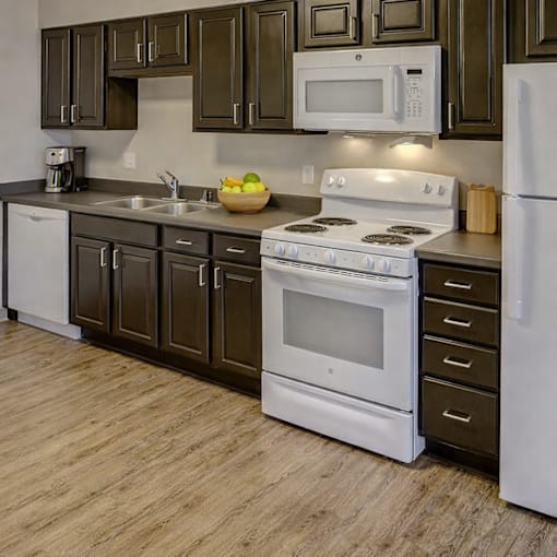 A kitchen with white appliances and brown cabinets.
