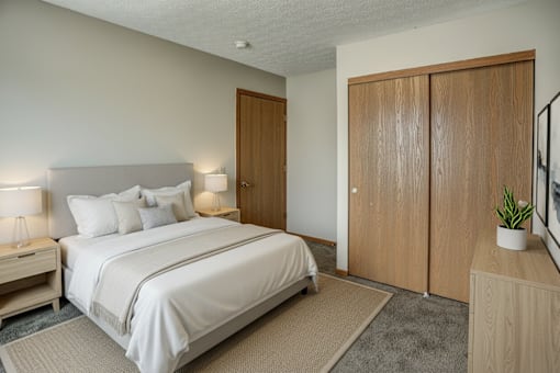A bedroom with a bed, nightstands, and a plant.
